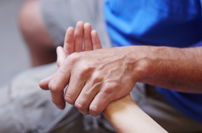 A photo of a patient's and a care provider's hands